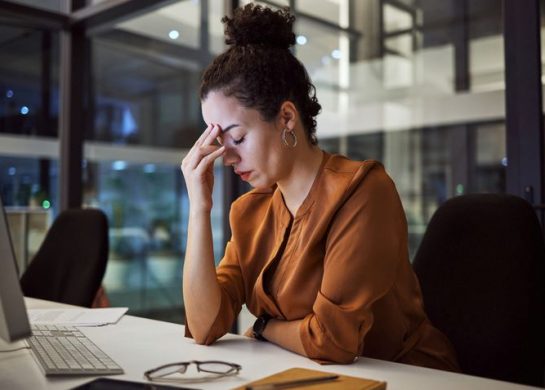 Kada je vreme da date otkaz; umorna žena prdržava prstima čelo u kancelariji na poslu