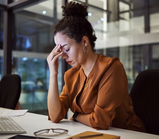 Kada je vreme da date otkaz; umorna žena prdržava prstima čelo u kancelariji na poslu